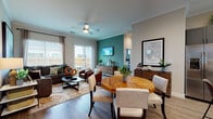 This single-story home offers a thoughtfully designed open-concept layout where the living, dining, and kitchen areas flow seamlessly together. The living room serves as the heart of the home, anchored by a bold teal accent wall, crown molding, a ceiling fan, and rich wood-look flooring. Large windows and a sliding glass door fill the space with natural light and provide direct access to a private outdoor patio. The sectional seating arrangement, flanked by leather accent chairs, creates an inviting and functional gathering space.

The kitchen is well-equipped with gray shaker-style cabinetry, granite countertops, stainless steel appliances, subway tile backsplash, and a breakfast bar with seating. Recessed lighting and crown molding add a polished finish. The adjacent dining area accommodates a round wood table, ideal for everyday meals or entertaining.

The primary bedroom is generously sized, featuring multiple windows, neutral tones, and wood-look flooring. The en-suite bathroom includes dark gray vanity cabinetry, granite countertops, wood-look tile flooring, and a glass-enclosed walk-in shower. A secondary bedroom provides comfortable accommodations with ample natural light and additional storage.