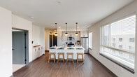 Located at 6122–6136 N Rural St in Indianapolis, Indiana, this single-floor unit showcases a contemporary design with a cohesive, neutral color palette throughout. The open-concept layout connects the kitchen and living area seamlessly, creating a spacious and functional main living space anchored by rich wood-look flooring.

The kitchen is a standout feature, equipped with stainless steel appliances including a refrigerator, range, and microwave. Gray shaker-style cabinetry with matte black hardware pairs with light countertops for a clean, modern aesthetic. A generously sized center island with an undermount sink provides ample seating for multiple bar stools and serves as a natural gathering point. Globe pendant lights suspended above the island add a stylish finishing touch. Multiple windows allow natural light to fill the space and offer views of the surrounding neighborhood.

The bedrooms feature plush carpeting and well-sized windows that bring in additional natural light. A barn-style sliding door adds a modern design element leading to one of the rooms. Both bathrooms maintain the unit's consistent aesthetic with white cabinetry, matte black hardware, undermount sinks, large mirrors, and wood-look flooring. One bathroom includes a tub-shower combination. The overall ambiance is clean, bright, and move-in ready.