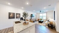 Located at 20 Mars Way in Saint Augustine, FL, this well-appointed 2-bedroom, 2-bathroom single-story residence offers a thoughtfully designed open-concept layout with modern finishes throughout. Wide-plank wood-style flooring flows seamlessly across all living areas, creating a cohesive and contemporary aesthetic.

The combined kitchen and living area serves as the heart of the home. The kitchen is equipped with stainless steel appliances, flat-front wood-toned cabinetry extending to the ceiling, a white subway tile backsplash, and a granite-topped island with bar seating — ideal for casual dining and entertaining. The adjoining living room is bright and inviting, featuring a ceiling fan, recessed lighting, and large windows that bring in generous natural light.

Both bedrooms are comfortably sized, with the primary bedroom offering a dedicated closet and ceiling fan. Each room benefits from natural light through well-placed windows. The primary bathroom includes a glass-enclosed walk-in shower, granite vanity, and wood-toned cabinetry, while the second bathroom features a shower/tub combination and a matching granite vanity. A dedicated closet provides additional storage. Clean white walls and consistent finishes throughout give this residence a bright, modern, and move-in-ready feel.