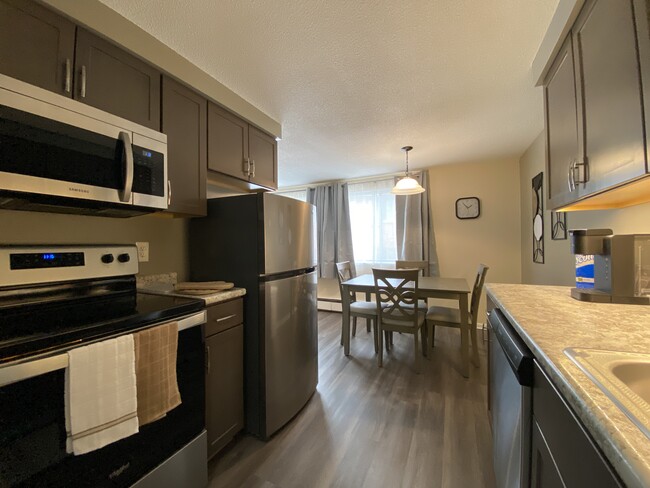 Full kitchen with large sized refrigerator, four burner stove and all dining & cookware - Avalon Suites Apartments