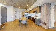 This 770 square foot apartment, located in TENTEN Downtown, embodies modern urban living with an industrial-chic aesthetic. The space is characterized by its exposed concrete ceilings, which add a raw, contemporary feel throughout. The open-concept layout maximizes the use of space, seamlessly blending the living areas.

The kitchen is a standout feature, boasting sleek wooden cabinetry with under-cabinet lighting, stainless steel appliances, and a contrasting gray lower cabinet design. It opens to a dining area with a wooden table and modern seating, perfect for entertaining or casual meals.

The bedroom, while compact at 90 square feet, makes efficient use of space with built-in storage. The industrial theme continues here with a concrete accent wall, balanced by warm wooden flooring and white walls.

The bathroom showcases a modern design with a spacious glass-enclosed shower, featuring clean lines and a minimalist aesthetic. Large format tiles and contemporary fixtures complete the look.

Throughout the apartment, large windows allow ample natural light, creating a bright and airy atmosphere. The juxtaposition of raw concrete elements with refined finishes like wooden floors and white walls creates a sophisticated urban retreat.

This apartment is ideal for those seeking a contemporary living space with character, offering the perfect blend of style and functionality in a prime downtown location.
