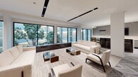 Located at 20 Burling Ln in New Rochelle, NY, this upscale resident lounge is a thoughtfully designed communal space that seamlessly blends elegance with functionality. Throughout the space, a striking herringbone-patterned tile floor in soft grey tones establishes a cohesive and refined aesthetic.

The modern kitchen area is outfitted with sleek, flat-panel grey cabinetry, white marble-veined countertops, a large undermount sink, a herringbone tile backsplash, and a wall-mounted television — ideal for entertaining and casual gatherings.

The main lounge area features expansive floor-to-ceiling windows framing lush courtyard views, flooding the space with natural light. Cream-toned sofas and glass-topped coffee tables create an airy, open seating arrangement. A dedicated media lounge offers a more intimate setting, with a pair of deep navy tufted curved sofas, flanking built-in shelving units, a herringbone accent wall, and dual wall-mounted screens.

A casual dining nook with marble-topped round tables and navy velvet chairs sits adjacent to large glazed windows overlooking the verdant courtyard, providing a bright and inviting spot for conversation or work. Completing the space is a full-sized billiards table, adding a recreational focal point to this well-appointed lounge.