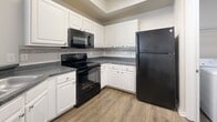 This single-story, 3-bedroom, 3-bathroom residence at 10135 Gate Parkway North in Jacksonville, Florida offers 1,220 square feet of thoughtfully laid-out living space. The home features consistent wood-look flooring throughout, neutral-toned walls, and textured ceilings that contribute to a clean, cohesive aesthetic. The living room is bright and open, benefiting from multiple windows with blinds that invite natural light, and is equipped with a ceiling fan for year-round comfort. The kitchen is well-appointed with white cabinetry, dark granite-style countertops, a tile backsplash, and a full suite of black appliances including a refrigerator, range, and over-the-range microwave. Each of the three bedrooms offers a comfortable layout with ceiling fans and access to the hallways. The primary bedroom measures 150 square feet and connects to closet space featuring wire shelving for organized storage. The three bathrooms include full bath configurations with tub-shower combos, vanities with dark countertops, and hardwood-style flooring. A dedicated in-unit laundry room with overhead wire shelving accommodates a full-size washer and dryer. Two hallways connect the rooms efficiently, and two closets provide ample storage throughout this functional and well-maintained home.