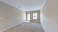 Located at 5300 Patron Pl in North Charleston, SC, this well-appointed 2-bedroom, 2-bathroom residence offers a comfortable and functional single-floor layout. The open-concept living and dining area is finished with plush wall-to-wall carpet, crown molding, and neutral tones throughout, creating a bright and welcoming atmosphere. A glass exterior door paired with an adjacent window floods the living space with natural light and provides access to an outdoor area.

The kitchen is efficiently designed with rich dark wood cabinetry, dark granite-style countertops, a center island, tile flooring, and a full suite of black appliances including a refrigerator, range, and dishwasher. Track lighting above illuminates the workspace, while a pass-through view connects the kitchen seamlessly to the living area.

The spacious primary bedroom features soft carpet, a ceiling fan, and generous closet space. The second bedroom is equally comfortable, also carpeted and finished with the same neutral palette, with access to a dedicated closet. Both bathrooms include tile flooring, rich wood vanities with stone-style countertops, and tub-shower combinations. Each bedroom benefits from dedicated closets with wire shelving for organized storage throughout.