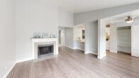Located at 209 21st Ave SW in Puyallup, WA, this one-bedroom, one-bathroom unit offers a thoughtfully arranged single-floor layout. The open-concept living room is a standout, featuring light hardwood-style flooring, a classic white fireplace with tile surround, and a sliding glass door that opens onto a private balcony with pleasant outdoor views of surrounding greenery. Natural light flows freely throughout the space, enhanced by additional windows fitted with blinds.

The galley-style kitchen is clean and modern, showcasing white shaker cabinetry, light countertops, a stainless steel sink, and stainless steel appliances including a refrigerator and electric range. A pass-through connects the kitchen to the living area, maintaining an open and connected feel. In-unit laundry is also visible within the kitchen corridor.

The bedroom is a comfortable, carpeted retreat finished in soft neutral tones, with a window for natural light and direct access to the bathroom. The full bathroom features wood-look vinyl flooring, a tub/shower combo, and clean white finishes. A dedicated closet and hallway complete the layout, making efficient use of the available space throughout this well-maintained Puyallup residence.