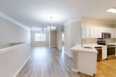 Located in Pearland, TX, this two-story home offers a well-designed layout across two floors. The main living level features an open-concept kitchen and living room that flow seamlessly together, creating a bright and functional shared space. The kitchen is outfitted with crisp white shaker-style cabinetry, white quartz countertops, a peninsula with a built-in sink, and a full suite of stainless steel appliances including a refrigerator, range, microwave, and dishwasher. Crown molding and an elegant chandelier add a refined touch to the living area, which is bathed in natural light from a large window. Light-toned hardwood-style flooring runs throughout the main living spaces, complementing the neutral warm-gray wall palette.

Both bedrooms are generously proportioned, each featuring crown molding, ceiling fans with lighting, hardwood-style floors, and natural light from windows with outdoor views. The primary bedroom is notably spacious, offering ample room for furnishings. Each bedroom is accompanied by a dedicated closet.

The full bathroom includes a soaking tub with tiled surround, a white vanity, and coordinating flooring. The attached garage on the ground floor provides convenient enclosed parking and additional storage space, accessed via an automatic opener.