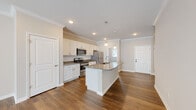 This single-story home offers a thoughtfully designed open-concept layout that seamlessly connects the kitchen, dining, and living areas. The kitchen serves as a central highlight, showcasing white shaker-style cabinetry, granite countertops with subtle veining, a subway tile backsplash, and a full suite of stainless steel appliances. A central island with a built-in sink and pendant lighting overhead adds both functionality and visual appeal. Crown molding and recessed lighting throughout the main living area lend an elevated, polished feel, while rich hardwood-style flooring flows consistently across the space.

The living area extends generously toward a wall of natural light, with a ceiling fan providing comfort overhead. Bedrooms are well-proportioned, featuring the same hardwood-style flooring, neutral walls, and bright windows dressed with blinds. The bathrooms are finished with granite vanity tops, white cabinetry, and chrome fixtures; one bath includes a walk-in shower. A dedicated laundry room offers wire shelving and utility hookups for added convenience. Overall, the home presents a clean, modern aesthetic with quality finishes throughout.