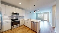 Located at 1701 Central Avenue in the heart of St. Petersburg, Florida, this well-appointed one-bedroom, one-bathroom residence offers a thoughtfully designed layout across a single floor. The open-concept kitchen and living area serves as the centerpiece of the home, featuring light wood-style flooring, a ceiling fan, and a large window with balcony access that fills the space with natural light and outdoor views. The modern kitchen is equipped with white cabinetry, a hexagonal tile backsplash, stainless steel appliances including a French door refrigerator, and a spacious peninsula with pendant lighting — ideal for both meal preparation and casual dining. A built-in shelving nook near the kitchen provides additional storage and display space. The bedroom is generously sized, finished with plush carpeting, a ceiling fan, and a large window framing lush outdoor greenery. It connects directly to a walk-in closet outfitted with wire shelving and hanging rods, offering ample storage. The full bathroom features a soaking tub with a tiled surround and a curved shower rod. Neutral tones and clean finishes throughout give the space a bright, cohesive, and move-in-ready ambiance.