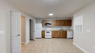 Located at 3014 S Adams St in Tallahassee, Florida, this single-floor space offers a practical and well-organized layout designed for comfortable everyday living. Light neutral tones on the walls and white baseboards create a clean, cohesive aesthetic throughout.

The kitchen is a functional highlight, featuring warm wood-toned cabinetry with sleek bar-pull hardware, light granite-style countertops, and a full suite of appliances including a refrigerator, electric range, over-the-range microwave, and dishwasher. Light ceramic tile flooring extends through the kitchen and connects seamlessly to the main living and corridor areas.

The spacious living areas are finished with the same tile flooring and include ceiling fans for climate comfort. Natural light filters in through windows fitted with horizontal blinds. A hallway connects the living spaces to the private rooms, maintaining a logical and efficient flow throughout the unit.

The bathrooms are finished with wood-look tile flooring, a tub-shower combination with a molded surround, and wood-toned vanity cabinetry with matching countertops. An in-unit laundry area provides added convenience. Textured ceilings are present in select areas, complementing the overall no-fuss, functional character of the space.