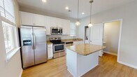 Located in Myrtle Beach, SC, this two-story home offers a thoughtfully designed layout with quality finishes throughout. The kitchen serves as a central highlight, featuring crisp white shaker cabinetry, granite countertops, a central island with pendant lighting, and a full suite of stainless steel appliances including a French door refrigerator, electric range, built-in microwave, and dishwasher. Light hardwood-style flooring runs through the main living areas, complemented by recessed lighting and natural light from multiple windows. The bedrooms are carpeted for comfort and include ceiling fans and generous closet space. The primary bedroom features a tray ceiling and an en-suite bathroom with a walk-in shower, granite vanity, and white cabinetry. A second full bathroom is also finished with granite countertops and includes a tub-shower combination. Additional living spaces on the main floor offer open, airy layouts with neutral tones and hardwood-style flooring, creating a versatile and welcoming environment. The overall aesthetic is clean and contemporary, making this Myrtle Beach home a well-rounded and functional residence.
