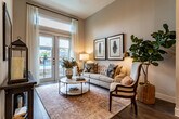 This single-floor residence showcases a thoughtfully designed open-concept layout that seamlessly connects the kitchen, dining, and living areas. The kitchen is a standout feature, outfitted with sleek dark wood-grain cabinetry extending to the ceiling, a classic white subway tile backsplash, and a full suite of stainless steel appliances including a gas range, built-in microwave, dishwasher, and French door refrigerator. A generous island with crisp white quartz countertops provides ample prep space and casual seating, while a series of glass pendant lights hang above, adding contemporary style. Tall ceilings throughout enhance the sense of openness and volume.

The living area is bathed in natural light, courtesy of full-height French doors that open to an outdoor view and allow views of a pool area beyond. Wood-look flooring grounds the space with warmth, while a ceiling fan adds comfort. The bedroom offers a cozy, well-appointed retreat with soft, neutral tones. The bathroom is finished with large-format tile flooring, a glass-enclosed walk-in shower, and a wood-toned vanity, and connects directly to an organized walk-in closet with built-in shelving.