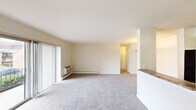 This single-floor, 2-bedroom, 1-bathroom unit offers a practical and comfortable layout across a well-utilized footprint. The open living room is a standout feature, finished with neutral-toned carpet and bathed in natural light from large sliding glass doors that open onto a private balcony overlooking greenery and the surrounding grounds. Baseboard heating and a wall-mounted HVAC unit ensure year-round climate control throughout the living area.

The kitchen is efficiently designed with warm wood cabinetry, granite-style countertops, tile flooring, and black appliances including a gas range and over-the-range microwave. A half-wall breakfast bar connects the kitchen to the adjacent living and dining area, enhancing the open feel of the shared space.

The primary bedroom is generously sized, featuring plush carpeting and ample room for furnishings, while the second bedroom offers a window with outdoor views and its own wall AC unit. A dedicated closet provides additional storage. The bathroom includes a full tub and shower combo with clean white tile surround. Throughout the unit, a neutral color palette and consistent finishes create a cohesive, move-in ready atmosphere.