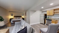 Located at 4041 Bluemel Rd in San Antonio, TX, this efficiently designed one-bedroom, one-bathroom unit makes excellent use of its single-floor layout. The open-concept floor plan seamlessly connects the living area, bedroom, and kitchen, creating a cohesive and functional living space.

The living room features wood-look plank flooring, a textured ceiling, and recessed lighting that keeps the space well-lit. A sliding glass door with vertical blinds allows natural light to filter in while providing access to the outdoors. The neutral gray walls and clean white baseboards throughout lend a modern, understated aesthetic.

The kitchen is well-appointed with warm-toned wooden cabinetry, granite-style countertops, and a full suite of stainless steel appliances, including a refrigerator, dishwasher, microwave, and range. The layout is compact yet practical, offering ample storage and counter space.

The bedroom area, open to the main living space, comfortably accommodates a large bed with a tufted headboard and includes bedside lighting for a warm, restful ambiance. A private door leads to the bathroom, ensuring a degree of separation within the open layout.

The consistent flooring, neutral color palette, and modern finishes unify the space, making it feel cohesive and inviting throughout.