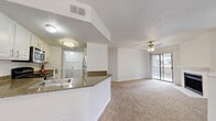 Located at 14300 Tandem Blvd in Austin, TX, this two-story, 2-bedroom, 2-bathroom home offers a well-organized layout spread across two levels. The main living floor hosts an open-concept kitchen and living room combination, where a peninsula with granite-style countertops and a built-in sink flows seamlessly into the carpeted living area. The kitchen is equipped with white cabinetry, a black range, and a stainless steel microwave. The living room features a ceiling fan with light, a fireplace with a white surround, and a sliding glass door that opens to a private balcony with outdoor views. Both bedrooms are carpeted and generously sized, each featuring ceiling fans, natural light from large windows with blinds, and a bright, neutral color palette. The primary bedroom offers comfortable proportions with ample room for furnishings. Both bathrooms include wood-look vinyl flooring, white vanities, framed mirrors, and a full tub-shower combination. A dedicated laundry room with side-by-side washer and dryer units adds everyday convenience. Textured ceilings are found throughout the home, contributing to its classic residential character.