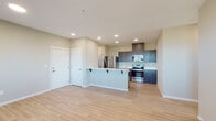 This single-floor unit presents a clean, contemporary design highlighted by light hardwood-style flooring and neutral warm-toned walls throughout. The open-concept living and kitchen area forms the heart of the space, where a peninsula with a built-in sink and breakfast bar seating serves as a natural divider. The kitchen is well-appointed with dark shaker-style cabinetry, light countertops, and a full suite of stainless steel appliances, including a French door refrigerator, electric range, and built-in microwave. Recessed lighting illuminates the space efficiently overhead.

The bedrooms are generously sized, each featuring large windows fitted with horizontal blinds that invite natural light and offer exterior views. At least one bedroom includes a sliding-door closet, providing practical storage. Two bathrooms serve the unit; one features a walk-in shower with a curved curtain rod and a vanity with dark cabinetry, while the second includes a tub-shower combination, a wide mirror, and a similarly styled dark-wood vanity with white countertop. The overall layout is functional and well-organized, reflecting a modern, move-in-ready aesthetic.