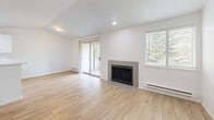 Located in Kent, WA, this one-bedroom, one-bathroom residence offers a thoughtfully designed single-floor layout. The open-concept living room serves as the heart of the home, featuring light wood-style flooring, a tile-surround fireplace, and a sliding glass door that opens to a private balcony with tree-lined views, filling the space with natural light. The kitchen is efficiently arranged with crisp white cabinetry accented by matte black hardware, white quartz countertops, light wood-style flooring, and black appliances including a refrigerator and electric range with overhead ventilation. A skylight adds an extra touch of brightness to the kitchen area. The bedroom is a comfortable retreat with plush carpeting, a window overlooking greenery, and a dedicated closet for storage. The bathroom maintains a clean, modern aesthetic with a white vanity, quartz countertop, matte black fixtures, wood-style flooring, and a full shower-tub combination. Throughout the residence, a neutral white palette and consistent modern finishes create a cohesive and inviting atmosphere, making this a well-appointed home in a convenient Kent location.