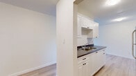 This single-floor, 2-bedroom, 1-bathroom unit offers a practical and clean layout designed for comfortable everyday living. The kitchen is fitted with crisp white cabinetry, a double stainless steel sink, dark countertops, and light hardwood-style flooring, providing a functional and tidy workspace. Upper and lower cabinet storage ensures ample space for kitchen essentials.

The living area is generously sized, finished with neutral carpet, and bathed in natural light through a large window and a sliding glass door that opens to a balcony with outdoor views—an inviting feature for relaxing or letting in fresh air. Baseboard heating runs along the perimeter, ensuring warmth throughout the colder months.

Both bedrooms are carpeted and feature large windows that draw in natural light and offer views of the surrounding neighborhood. The primary bedroom includes a sliding-door closet with a full-width hanging rod, offering solid storage capacity. The second bedroom is similarly proportioned and well-lit.

A connecting hallway links the bedrooms to the full bathroom, which is equipped with a full-size soaking tub and a clean, bright tub surround. Throughout the unit, neutral tones, white trim, and textured ceilings contribute to a bright, understated aesthetic that is easy to personalize.