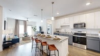 Located at 3050 Mellennium Way in Kissimmee, FL, this thoughtfully designed 2-bedroom, 2-bathroom residence offers a comfortable and modern living experience across a single floor. The open-concept kitchen and living area serves as the heart of the home, showcasing a large granite-topped island with bar seating, white upper cabinetry, gray lower cabinets, a subway tile backsplash, and a full suite of stainless steel appliances. Pendant lighting above the island adds a polished touch, while wood-look flooring flows seamlessly throughout the main living area, which is brightened by multiple windows and a ceiling fan. The primary bedroom is a generous retreat featuring plush carpeting, a ceiling fan, and direct access to a dedicated walk-in closet with built-in shelving. The second bedroom is equally comfortable, with soft carpet and ample natural light. Both bathrooms are finished with granite countertops and gray cabinetry, with one featuring a tub-shower combination and tile surround. Additional highlights include two closets, a utility room, and a clean, neutral color palette throughout that creates a bright and welcoming ambiance ideal for everyday living.
