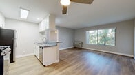 Located in the Valley Village neighborhood of Los Angeles, this 2-bedroom, 3-bathroom single-story home offers a well-designed layout with a clean, modern aesthetic throughout. The open-concept kitchen and living area serve as the heart of the home, featuring light hardwood-style flooring, neutral gray walls, and a ceiling fan overhead. The kitchen is outfitted with white shaker cabinetry, gray countertops, stainless steel appliances including a gas range, built-in microwave, and refrigerator, as well as a skylight that fills the space with natural light. A peninsula with a sink connects the kitchen to the living area, which benefits from a large window overlooking lush greenery. Both bedrooms are carpeted and equipped with ceiling fans, and each offers window views of the surrounding trees, creating a calm, nature-connected atmosphere. The primary bedroom includes access to a dedicated walk-in closet with built-in shelving. Three bathrooms provide convenience and privacy for residents, each featuring tiled flooring and tub-shower combinations with white fixtures and chrome hardware. The overall ambiance is bright, functional, and comfortable, making this a practical and inviting home in the heart of Los Angeles.