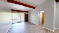 Located at 144 Highland Ave in East Lansing, MI, this one-bedroom, one-bathroom unit offers a practical and comfortable layout across a single floor. The living room is a standout space, characterized by distinctive exposed wood beams that add architectural character to the otherwise neutral, light-toned interior. Light luxury vinyl plank flooring runs throughout, providing a cohesive and easy-to-maintain surface. A sliding glass door floods the living area with natural light and provides views of the surrounding greenery. Baseboard heating and a wall-mounted air conditioning unit ensure year-round comfort. The galley-style kitchen is efficiently designed with warm wood cabinetry, dark granite-style countertops, a double-basin sink, and full appliances including an electric range and refrigerator — offering ample storage and prep space. The bedroom is a comfortable size, featuring a skylight for added brightness, a built-in closet with sliding doors, and continued wood beam detailing. The full bathroom includes a tiled tub/shower combination with classic white tile surround. A dedicated closet completes the unit's storage offerings, making this a well-organized and functional home.
