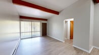 Located at 144 Highland Ave in East Lansing, MI, this one-bedroom, one-bathroom unit offers a practical and comfortable layout across a single floor. The living room is a standout space, characterized by distinctive exposed wood beams that add architectural character to the otherwise neutral, light-toned interior. Light luxury vinyl plank flooring runs throughout, providing a cohesive and easy-to-maintain surface. A sliding glass door floods the living area with natural light and provides views of the surrounding greenery. Baseboard heating and a wall-mounted air conditioning unit ensure year-round comfort. The galley-style kitchen is efficiently designed with warm wood cabinetry, dark granite-style countertops, a double-basin sink, and full appliances including an electric range and refrigerator — offering ample storage and prep space. The bedroom is a comfortable size, featuring a skylight for added brightness, a built-in closet with sliding doors, and continued wood beam detailing. The full bathroom includes a tiled tub/shower combination with classic white tile surround. A dedicated closet completes the unit's storage offerings, making this a well-organized and functional home.