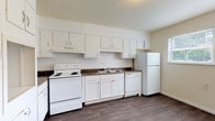 Located in College Park, GA, this two-floor residence offers a practical and functional layout across its multiple levels. The main living area features rich, dark wood-style flooring that extends throughout, complemented by neutral-toned walls and multiple windows that allow natural light to fill the space. A sliding glass door provides direct outdoor access, enhancing the open feel of the living area.

The kitchen is well-appointed with abundant white cabinetry, dark countertops, and a full suite of white appliances including an electric range, dishwasher, and refrigerator. The layout provides ample storage and workspace for everyday cooking needs.

The bedrooms are carpeted for added comfort and feature windows with views of the surrounding neighborhood, offering a quiet and bright retreat. Two bathrooms serve the space — one features a walk-in shower with white tile walls and a mosaic tile floor, while the second includes a dark-stained wood vanity with a white countertop and a tub-shower combination. Both bathrooms continue the wood-style flooring found throughout the home.

A dedicated laundry area includes overhead cabinetry and washer/dryer hookups, adding convenience to the home's overall functional design. The space presents a clean, move-in ready environment suited for comfortable everyday living.