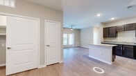 This single-story, 2-bedroom, 2-bathroom residence in Kyle, TX offers a thoughtfully designed open-concept layout with consistent wood-look flooring throughout the main living areas. The combined kitchen and living room serves as the heart of the home, where a well-appointed kitchen features dark espresso cabinetry, granite-style countertops, black appliances, recessed lighting, and a central island that provides additional prep space and seating. The living area flows naturally from the kitchen, bathed in natural light from a set of glass-panel doors that open to the outside and are fitted with a ceiling fan overhead.

Both bedrooms are comfortably sized, with the primary bedroom offering a generous walk-in closet equipped with wire shelving for organized storage. The secondary bedroom includes a closet and a window that fills the room with abundant natural light. Each bathroom is finished with tile flooring, dark wood vanity cabinetry, granite countertops, large mirrors, and a walk-in glass shower. Neutral, warm-toned walls run throughout the residence, complementing the light flooring and white trim for a clean, cohesive aesthetic. A hallway connects the private areas of the home, completing this efficient and functional floor plan.