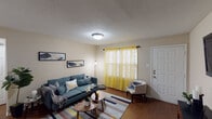 This single-story residence offers a thoughtfully arranged floor plan with distinct living, dining, kitchen, bedroom, and bathroom areas. The living room serves as the heart of the home, featuring warm hardwood-style flooring, a textured ceiling, and a front-facing window dressed with vibrant yellow sheer curtains that bathe the space in natural light. A flush-mount ceiling light provides additional illumination, and the room comfortably accommodates a full seating arrangement with a sofa, accent chair, and coffee table.

The kitchen is well-equipped, showcasing rich dark cabinetry paired with granite-style countertops and stainless steel appliances, including a range and over-the-range microwave. A double-basin sink sits beneath a window, enhancing the workspace's functionality.

The two bedrooms are carpeted for comfort, each featuring a ceiling fan or dedicated lighting, closet space, and windows for natural light. The rooms offer a calm, restful atmosphere suitable for relaxation.

Both bathrooms are efficiently laid out, each with a vanity featuring a dark cabinet base and white countertop, a tub-shower combination, and tasteful décor accents that contribute to a clean, cohesive aesthetic throughout the home.