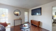 This single-floor residence offers a thoughtfully organized layout that connects key living areas in a functional and cohesive flow. The living room serves as the central gathering space, featuring rich wood-look flooring, neutral walls, a textured ceiling, and windows with plantation shutters that allow natural light to filter in. A wall-mounted television and a dedicated entry console area add both practicality and style to the room.

Adjacent to the living area, a separate dining nook provides an intimate setting for meals, with hardwood-style flooring continuing throughout. The galley-style kitchen is efficiently designed with dark wood cabinetry, granite-look countertops, a tile backsplash, and black appliances, including a range, microwave, refrigerator, and dishwasher.

The bedroom is carpeted for comfort and includes a ceiling fan, windows with blinds, and access to a walk-in closet, offering ample storage. The bathroom features a full tub-and-shower combination, a dark wood vanity with granite-style countertops, and wood-look tile flooring, completing the cohesive design found throughout the space.