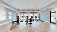 Located at 1005 Sonoran Cir in Summerville, SC, this fitness center offers a well-appointed, single-floor workout facility designed to accommodate a comprehensive range of exercise needs. The space is finished with soft blue-gray walls, crown molding, and neutral toned flooring, creating a clean and inviting atmosphere throughout.

A floor-to-ceiling window wall along one side of the room floods the interior with natural light while providing views of the surrounding community. Recessed lighting and dual ceiling fans ensure the space remains bright and comfortable during any workout. Large mirrors are strategically placed to enhance the sense of openness and assist with proper form during training.

The fitness center is outfitted with a solid selection of cardio equipment, including multiple treadmills, elliptical trainers, and a rowing machine. Strength training is well represented with a variety of cable machines, weight benches, and a free weight rack stocked with dumbbells. The open layout allows for easy movement between stations without feeling crowded.

Double glass French doors connect the fitness center to an adjacent amenity space, contributing to an integrated community feel. The overall design balances functionality with aesthetic appeal, making this a polished and practical facility for residents of the Summerville community.