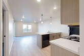 Located at 3201 N. Martindale Rd in Sioux Falls, SD, this thoughtfully designed 2-bedroom, 2-bathroom unit offers a clean, modern aesthetic across a single floor. The open-concept kitchen and living area serves as the heart of the home, featuring light wood-look flooring, recessed lighting, and stylish pendant lights over a peninsula island with a built-in sink and ample counter space. Taupe cabinetry, light quartz-style countertops, and black appliances — including a refrigerator, range, microwave, and dishwasher — complete the well-equipped kitchen. The adjoining living area is bright and open, with a window that brings in natural light. Both bedrooms are carpeted and include ceiling fans and windows for ventilation and natural light. The primary bedroom offers a comfortable, private retreat with direct access to its own bathroom. The bathrooms are finished with tile flooring, vanities with white countertops, and taupe cabinetry with dark hardware. A dedicated laundry space houses a stacked Whirlpool washer and dryer, adding everyday convenience. The unit also includes a hallway, closet, and a cohesive neutral color palette throughout, creating a clean and contemporary living environment.