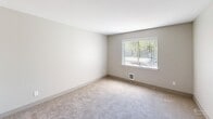 Located at 22623 91st Way S in Kent, Washington, this single-floor, 3-bedroom, 2-bathroom home presents a clean, modern interior with a thoughtfully designed layout. The home features a central hallway finished with light luxury vinyl plank flooring and a flush-mount ceiling light fixture, connecting the main living areas with ease. The bedrooms are carpeted in neutral tones, providing a comfortable and quiet atmosphere. The spacious primary bedroom offers ample room for furnishings, while the two additional bedrooms each feature windows with views of surrounding greenery, allowing natural light to fill the spaces. Two closets provide convenient storage throughout the home. The two bathrooms are well-equipped: one features a full tub-shower combo with a curved curtain rod, a quartz-topped vanity, and an in-unit washer and water heater, while the second offers a walk-in shower with sleek sliding glass doors and tile-style flooring. Neutral gray walls and white trim carry a consistent, clean aesthetic throughout the entire home. The overall ambiance is bright, understated, and functional, making this Kent residence a versatile and move-in-ready space.