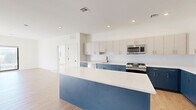 Located at 555 Northfield Avenue in West Orange, NJ, this thoughtfully designed 2-bedroom, 2-bathroom residence offers a contemporary open-concept layout across a single floor. The striking kitchen serves as the heart of the home, featuring two-tone cabinetry with bold blue lower cabinets and crisp white uppers, a large quartz-topped island, textured tile backsplash, and a full suite of stainless steel appliances. Light wood-tone flooring flows seamlessly throughout, tying together the open kitchen and living area. The sun-filled living space opens to a private balcony through sliding glass doors, inviting natural light and outdoor views. The generously sized primary bedroom includes a double-door closet, while both bedrooms feature clean white walls and large windows with exterior views. The bathrooms are finished in a modern style, showcasing floating vanities with blue-grey cabinetry, gold hardware accents, matte black fixtures, and round gold-framed mirrors. Additional highlights include a den, an in-unit laundry room, and an impressive six closets providing exceptional storage. Recessed lighting throughout enhances the bright, airy ambiance of this well-appointed residence.
