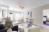 This single-floor residence offers a cohesive, contemporary design highlighted by light wood-look flooring, neutral warm-toned walls, and abundant natural light throughout. A welcoming entry hallway leads into the main living areas, where the open-concept living room impresses with crown molding, a ceiling fan, and large windows dressed in elegant striped drapes that flood the space with daylight. The living room features a dedicated reading nook anchored by a plush accent chair and additional windows with plantation shutters, creating a bright and inviting retreat.

The kitchen is well-equipped with white shaker-style cabinetry, white quartz countertops, a subway tile backsplash, and stainless steel appliances including a range, microwave, and dishwasher. A peninsula counter connects seamlessly to the dining area, which features crown molding and space for a round dining table. The bedroom is generously sized with a ceiling fan, carpeted flooring, ample natural light from a window with blinds, and access to a closet. The bathroom includes a soaking tub and shower combo, a white vanity with quartz countertops, and wood-look tile flooring. Throughout, the design maintains a clean, modern aesthetic with consistent finishes and tasteful detailing.