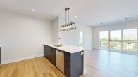 Located at 4 N Hickory Ave in Arlington Heights, Illinois, this thoughtfully designed single-floor residence offers a well-appointed layout with modern finishes throughout. Light oak hardwood flooring flows seamlessly across the living areas, creating a warm and cohesive aesthetic.

The kitchen serves as a central focal point, anchored by a large island with a crisp white quartz countertop, an undermount sink, and matte black hardware. Dark cabinetry contrasts elegantly with warm wood upper cabinets, while a full suite of stainless steel appliances — including a refrigerator, gas range, microwave, and dishwasher — ensures full functionality. An industrial-style rectangular pendant light adds a striking design element above the island.

The living area opens to a private balcony through sliding glass doors, offering scenic views of the surrounding Arlington Heights landscape, including lush greenery and the neighborhood skyline. A second room also features direct balcony access and large windows that flood the space with natural light.

The bathroom is finished with large-format stone tile flooring, a wood-toned vanity, and a glass-enclosed walk-in shower with white subway tile walls. Additional highlights include a generously sized walk-in closet with built-in wire shelving and multiple rooms benefiting from large windows with bright outdoor views.