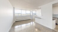 Located at Fowler Drive in Mississauga, Ontario, this well-appointed 2-bedroom, 1-bathroom unit offers a clean, modern living environment across a single floor. The open-concept kitchen and living area forms the heart of the space, where floor-to-ceiling windows along one full wall flood the interior with natural light and frame sweeping outdoor views. The kitchen is thoughtfully designed with white shaker-style cabinetry, dark countertops, a light grey subway tile backsplash, polished tile flooring, and a full suite of stainless steel appliances including a French door refrigerator, stove, and built-in microwave. The spacious living room features classic parquet wood flooring that extends throughout the unit, complemented by crisp white walls and baseboard heating. Both bedrooms are comfortably sized, bright, and finished with the same warm parquet flooring and neutral tones. The bathroom is finished with white subway tile from floor to ceiling, a soaking tub with shower, and chrome fixtures. A dedicated closet provides additional storage, while the balcony offers a private outdoor retreat with open views of the surrounding landscape.