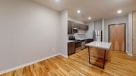 Located at 1011 S Saddle Creek Rd in Omaha, Nebraska, this thoughtfully designed single-floor unit offers a clean, contemporary aesthetic throughout. The kitchen is a standout feature, outfitted with rich dark-toned cabinetry, a full suite of stainless steel appliances including a refrigerator, electric range, built-in microwave, and dishwasher, all set against a classic white tile backsplash. Light-toned granite countertops and a kitchen island with a marble-style top provide ample prep and dining space. Warm hardwood-style flooring runs throughout the main living and kitchen areas, adding a welcoming character to the space. The bedroom is finished with soft carpeting and features a large floor-to-ceiling window that floods the room with natural light and offers views of the surrounding neighborhood. The bathroom is well-appointed with a full tub-shower combination, dark wood vanity cabinetry, a granite-topped countertop, an integrated sink, and open shelving for convenient storage. Neutral gray walls and recessed lighting throughout contribute to a bright, modern ambiance that makes the entire unit feel open and move-in ready.