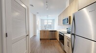 Located at 808 Chapel Street in the heart of New Haven, CT, this efficiently designed single-floor unit offers a thoughtful open-concept layout that maximizes every square foot. The space is unified by warm-toned wood-look flooring that runs continuously throughout, complemented by bright white walls that enhance the overall sense of light and openness.

The kitchen is a standout feature, outfitted with light wood cabinetry extending to the ceiling for ample storage, crisp white quartz countertops, and a full suite of stainless steel appliances including a refrigerator, electric range, over-the-range microwave, and dishwasher. A peninsula with an undermount sink serves as both a functional workspace and a natural divider between the kitchen and the open living area. Track lighting overhead ensures the kitchen is well-illuminated, while large windows at the far end of the unit flood the space with natural light.

The open living area provides a flexible, unobstructed space with clean walls ready for personalization. The bathroom continues the modern aesthetic with light wood cabinetry, white countertops, black hardware accents, and a large mirror above the vanity. Louvered closet doors add a classic touch near the entryway. The overall design is clean, contemporary, and move-in ready.