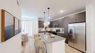 Located at 6519 Kings Glen Drive in Humble, TX, this contemporary 2-bedroom, 3-bathroom multi-story home is thoughtfully designed across three floors. The ground floor provides an entry point, while the main living level features an open-concept layout combining the kitchen, dining, and living areas. The kitchen is a standout, showcasing dark wood cabinetry, granite countertop island with bar seating, stainless steel appliances, and elegant pendant lighting. The adjoining dining nook benefits from abundant natural light through multiple windows and a glass door. The living room is bright and airy, with light hardwood flooring, recessed lighting, and large windows fitted with white blinds throughout. Upstairs, the spacious primary bedroom includes a ceiling fan, generous natural light, a walk-in closet with extensive shelving, and an en-suite bathroom featuring a dual granite vanity and glass-enclosed shower. The second bedroom is equally well-appointed with large windows and a ceiling fan. Three full bathrooms serve the home, each finished with quality fixtures and granite surfaces. Light wood flooring flows seamlessly throughout, contributing to the clean, modern aesthetic of this well-appointed residence.