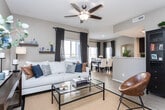 Located at 622 W 1428 S St in Orem, Utah, this well-appointed single-floor home offers 2 bedrooms, 1 bathroom, a dedicated office, and a thoughtfully designed open-concept living, dining, and kitchen area. The living room features light hardwood-style flooring, neutral gray walls, a ceiling fan with a decorative fixture, floating wood shelves, and large windows dressed with plantation shutters and navy drapes that invite generous natural light. The adjoining dining area continues the bright, airy feel with large windows overlooking greenery outside. The galley-style kitchen is outfitted with rich dark cabinetry, stainless steel appliances, light countertops, and light plank flooring, offering an efficient and stylish workspace. The spacious primary bedroom is carpeted and features plantation shutters, ample natural light, and a calm neutral palette. The second bedroom, also carpeted with a bright window, functions flexibly as an office or guest room. The bathroom presents dark wood vanity cabinetry, white countertops, light tile flooring, and a full tub-shower combination. Throughout, the home maintains a cohesive, modern aesthetic with warm neutral tones, consistent window treatments, and practical, comfortable finishes.