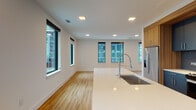 Located at 1150 Spring St NW in Atlanta's vibrant Midtown neighborhood, this single-floor unit showcases a clean, contemporary design throughout. The open-concept kitchen serves as a central hub, featuring a large island with a white quartz countertop and an integrated stainless steel sink with a professional-style faucet. Navy cabinetry pairs with warm wood upper cabinets, complemented by stainless steel appliances including a refrigerator, range, and microwave. Recessed lighting and multiple black-framed windows flood the space with natural light while offering views of the surrounding cityscape.

Light wood-style flooring flows through the main living areas and hallway, creating a cohesive and airy feel. The hallway connects the rooms efficiently, lined with dark-finished doors that add a modern contrast to the crisp white walls. Bedrooms feature neutral carpeting, ceiling fans, and windows with urban views. The primary suite includes a spacious walk-in closet with wire shelving and an en-suite bathroom outfitted with a glass-enclosed shower, dark tile surround, wood-tone flooring, and a double vanity with dark cabinetry. A second bathroom offers a soaking tub with a similarly styled dark tile surround. A private balcony provides outdoor access with open views of the Midtown Atlanta skyline.