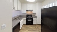 Located at 1501 E Grand Ave in Escondido, California, this single-floor unit offers a well-organized layout with a thoughtful blend of comfort and functionality. The living area is bright and airy, featuring durable wood-style flooring, vertical blinds, and multiple windows alongside a sliding glass door that fills the space with natural light and provides access to the outdoors. A wall-mounted HVAC unit ensures year-round climate control. The kitchen is efficiently designed with crisp white shaker-style cabinetry, gray countertops, a double-basin sink, and black appliances including a range with overhead exhaust hood, dishwasher, and refrigerator — all set atop matching wood-style flooring. The bedroom offers a calm, neutral atmosphere with plush wall-to-wall carpeting, smooth beige walls, and a window that invites natural light. The textured ceiling adds a classic touch consistent throughout the unit. The bathroom is clean and functional, featuring a full tub and shower combination with a curved curtain rod, a single-sink vanity with a dark countertop, a large mirror, and wood-style flooring. The overall aesthetic is neutral and move-in ready, presenting a practical and comfortable living environment in Escondido.