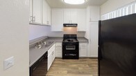 Located at 1501 E Grand Ave in Escondido, California, this single-floor unit offers a well-organized layout with a thoughtful blend of comfort and functionality. The living area is bright and airy, featuring durable wood-style flooring, vertical blinds, and multiple windows alongside a sliding glass door that fills the space with natural light and provides access to the outdoors. A wall-mounted HVAC unit ensures year-round climate control. The kitchen is efficiently designed with crisp white shaker-style cabinetry, gray countertops, a double-basin sink, and black appliances including a range with overhead exhaust hood, dishwasher, and refrigerator — all set atop matching wood-style flooring. The bedroom offers a calm, neutral atmosphere with plush wall-to-wall carpeting, smooth beige walls, and a window that invites natural light. The textured ceiling adds a classic touch consistent throughout the unit. The bathroom is clean and functional, featuring a full tub and shower combination with a curved curtain rod, a single-sink vanity with a dark countertop, a large mirror, and wood-style flooring. The overall aesthetic is neutral and move-in ready, presenting a practical and comfortable living environment in Escondido.