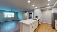 This single-floor residence showcases a clean, contemporary design with a well-planned open layout. The kitchen serves as a central hub, featuring white shaker-style cabinetry with brushed nickel hardware, bright white quartz countertops, and a large peninsula island with an undermount sink. Stainless steel appliances, including a refrigerator, gas range, microwave, and dishwasher, complete the kitchen. Recessed lighting illuminates the space throughout. Light wood-tone flooring runs through the main living areas, creating a cohesive flow from the kitchen into the spacious living area, which benefits from natural light through windows and is equipped with a ceiling fan.

An in-unit stacked washer and dryer is conveniently accessible from the main living space. Two bathrooms are finished consistently with white vanity cabinetry, quartz countertops, undermount sinks, and large mirrors with brushed nickel fixtures. The bedrooms feature neutral carpet flooring and windows that allow natural light. The overall color palette of soft blues, greiges, and white tones contributes to a clean, calm, and modern ambiance throughout.