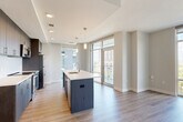 Located in McLean, VA, this thoughtfully designed two-bedroom, two-bathroom residence offers a comfortable and modern living experience across a single floor. Light hardwood-style flooring flows throughout the main living areas, while a bright, welcoming hallway with recessed lighting connects the rooms with ease.

The open-concept kitchen and dining area serve as the heart of the home, showcasing dark espresso cabinetry, a subway tile backsplash, stainless steel appliances, and a large center island with a white quartz countertop and pendant lighting overhead. Floor-to-ceiling windows flood the space with natural light and offer expansive urban views, while a glass-paneled door opens directly to the private patio.

The spacious living room is clean and neutral, with ample wall space and recessed lighting creating a versatile backdrop. Both bedrooms feature plush carpeting and large windows that frame lush tree canopy views, bringing nature indoors. The primary bedroom includes generous closet space.

The two bathrooms are finished with light tile flooring, dark wood vanities, white countertops, and classic white tile tub surrounds. A dedicated laundry area and multiple closets provide practical storage throughout. This residence combines contemporary finishes with a functional, well-organized layout.