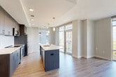 Located in McLean, VA, this thoughtfully designed two-bedroom, two-bathroom residence offers a comfortable and modern living experience across a single floor. Light hardwood-style flooring flows throughout the main living areas, while a bright, welcoming hallway with recessed lighting connects the rooms with ease.

The open-concept kitchen and dining area serve as the heart of the home, showcasing dark espresso cabinetry, a subway tile backsplash, stainless steel appliances, and a large center island with a white quartz countertop and pendant lighting overhead. Floor-to-ceiling windows flood the space with natural light and offer expansive urban views, while a glass-paneled door opens directly to the private patio.

The spacious living room is clean and neutral, with ample wall space and recessed lighting creating a versatile backdrop. Both bedrooms feature plush carpeting and large windows that frame lush tree canopy views, bringing nature indoors. The primary bedroom includes generous closet space.

The two bathrooms are finished with light tile flooring, dark wood vanities, white countertops, and classic white tile tub surrounds. A dedicated laundry area and multiple closets provide practical storage throughout. This residence combines contemporary finishes with a functional, well-organized layout.