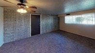 Located at 1002 Lake St in Kent, Ohio, this single-floor unit offers a straightforward and functional layout across several well-defined rooms. The living area makes an immediate impression with its full brick accent wall, dark front entry door, and a ceiling fan with a light fixture overhead. Natural light filters in through a window fitted with vertical blinds, and plush dark carpeting extends throughout the space, adding warmth underfoot. The textured ceiling is consistent throughout the unit, lending a cohesive character to the interior. The bedrooms are comfortably sized, each featuring carpeted floors, neutral-toned walls, and windows with blinds that allow for adjustable natural light. Ventilation registers are visible in the ceilings, and the rooms offer clean, open wall space suitable for a variety of furniture arrangements. The kitchen is equipped with dark wood cabinetry arranged in an L-shape, providing ample upper and lower storage. Light-toned countertops, a stainless steel sink, a gas range, and a full-size refrigerator complete the kitchen's practical setup. Vinyl flooring finishes the kitchen area. The bathroom features a full tub and shower combination with white tile surround, a toilet, and towel bars, all presented in a clean, neutral palette. The overall layout, as seen in the dollhouse view, is efficient and well-connected.