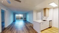 This contemporary apartment in Newport Beach offers a spacious 1010 square feet of living area on a single floor. The open-concept design seamlessly integrates the kitchen and living room, creating a fluid and airy ambiance. The kitchen is a highlight, featuring sleek white cabinetry, stainless steel appliances, and a practical island with a sink, perfect for both meal preparation and casual dining.

Throughout the apartment, beautiful hardwood flooring adds warmth and elegance to each room. The primary bedroom is particularly generous, boasting 210 square feet of space. Both bedrooms feature large windows that allow ample natural light, enhancing the sense of openness. Built-in closets with mirrored sliding doors offer practical storage solutions.

The two bathrooms are modern and pristine, with white fixtures and tiled surroundings. One bathroom includes a shower-tub combination, while the other offers a standalone shower, providing versatility for residents' preferences.

The apartment's neutral color palette, predominantly white walls, and ceilings create a blank canvas for personal decoration. Recessed lighting in the kitchen and ceiling fans in other rooms contribute to the overall modern aesthetic while ensuring comfort. This well-designed space combines functionality with style, making it an ideal home in the desirable Newport Beach area.