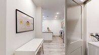 This well-designed one-bedroom, one-bathroom unit offers a thoughtfully organized single-floor layout that maximizes functionality within a compact footprint. The open-concept kitchen and living area serves as the heart of the unit, featuring light wood-look luxury vinyl flooring, recessed lighting, and a clean, modern aesthetic with crisp white walls throughout. The kitchen is equipped with stainless steel appliances, including a French door refrigerator with ice maker, an electric range, and a microwave. Light taupe cabinetry pairs with grey quartz countertops and a subway tile backsplash, while a peninsula island provides additional prep space and casual seating. The living area benefits from a private exterior entry door alongside a large window, inviting natural light and offering ceiling fan comfort. The bedroom is carpeted for warmth and comfort, featuring two windows that allow ample natural light, a ceiling fan, and a dedicated closet. The bathroom includes a full tub-shower combination with built-in shelving, wood-look flooring, and light wood cabinetry for overhead storage. The overall ambiance is clean, contemporary, and efficiently designed.