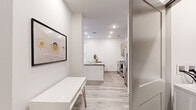 This well-designed one-bedroom, one-bathroom unit offers a thoughtfully organized single-floor layout that maximizes functionality within a compact footprint. The open-concept kitchen and living area serves as the heart of the unit, featuring light wood-look luxury vinyl flooring, recessed lighting, and a clean, modern aesthetic with crisp white walls throughout. The kitchen is equipped with stainless steel appliances, including a French door refrigerator with ice maker, an electric range, and a microwave. Light taupe cabinetry pairs with grey quartz countertops and a subway tile backsplash, while a peninsula island provides additional prep space and casual seating. The living area benefits from a private exterior entry door alongside a large window, inviting natural light and offering ceiling fan comfort. The bedroom is carpeted for warmth and comfort, featuring two windows that allow ample natural light, a ceiling fan, and a dedicated closet. The bathroom includes a full tub-shower combination with built-in shelving, wood-look flooring, and light wood cabinetry for overhead storage. The overall ambiance is clean, contemporary, and efficiently designed.